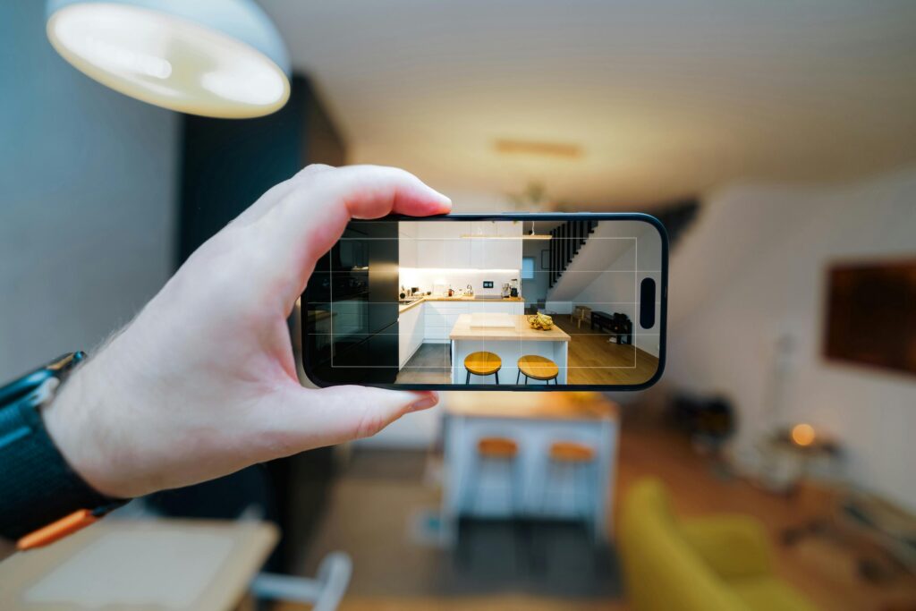 A smartphone in focus capturing a modern kitchen interior, showcasing real estate potential.